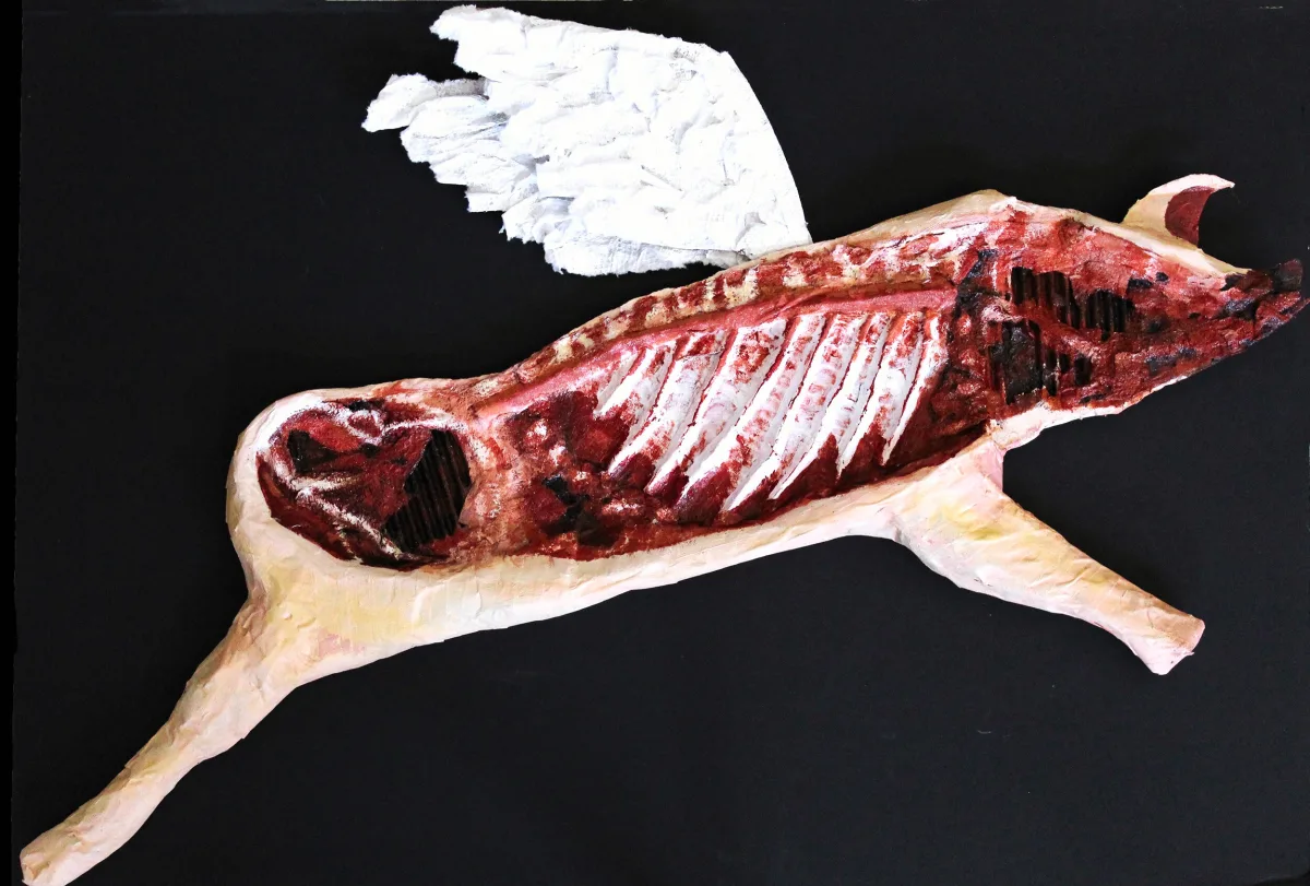 Sculptural butchered pig assembled from cardboard and painted paper